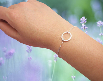 Two silver Minimalist Circle Bracelets by Maramalive™ on a person's hand.