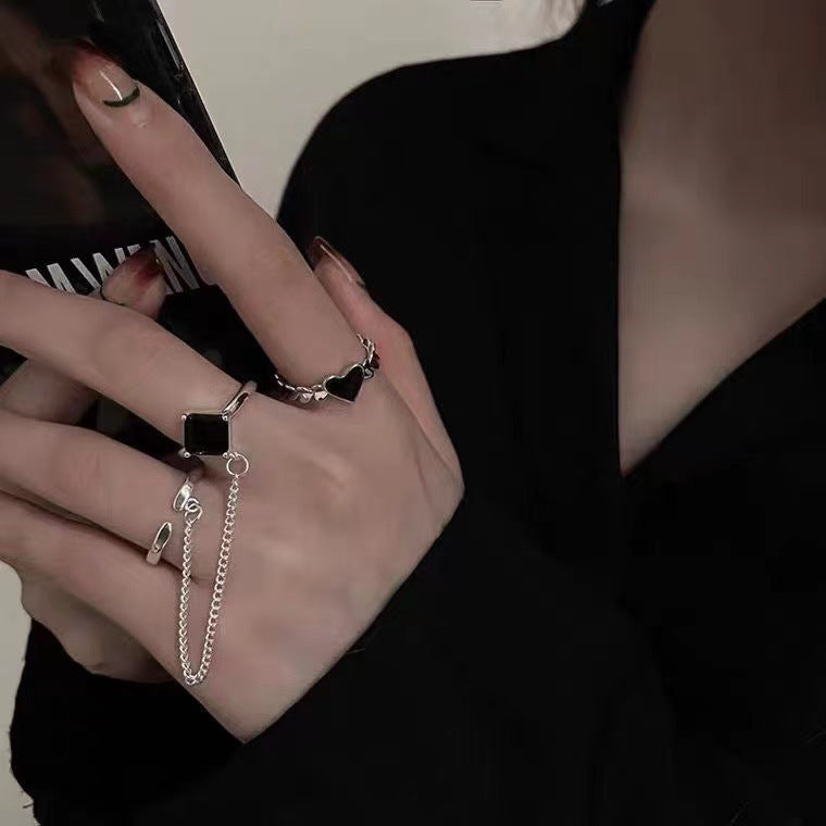 A woman wearing a Maramalive™ Women's Ins Love Minority Fashion Ring with a black stone and silver chain.