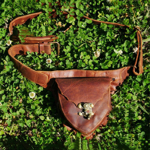 A brown leather Medieval Steampunk Vintage Heart Belt Satchel by Maramalive™ laying in the grass.