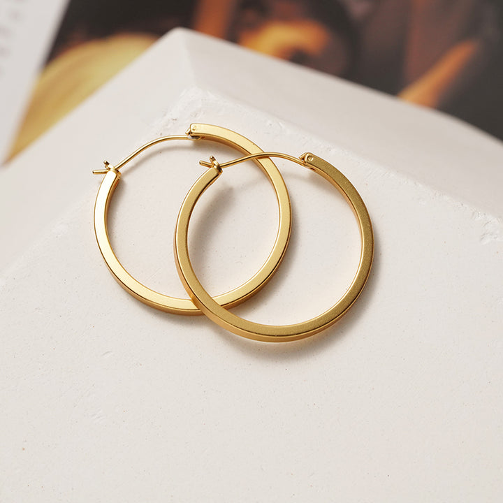 A pair of Maramalive™ Minimalist Circle Ear Buckle earrings on a white surface.