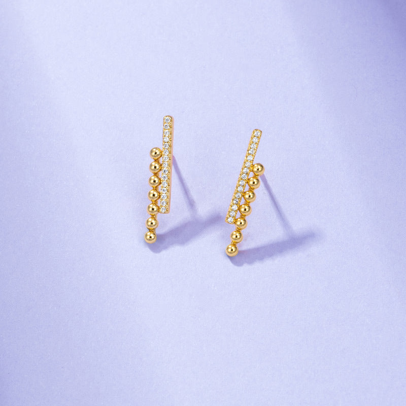 A pair of Maramalive™ Gold-Plated Minimalist Earrings on a purple background.