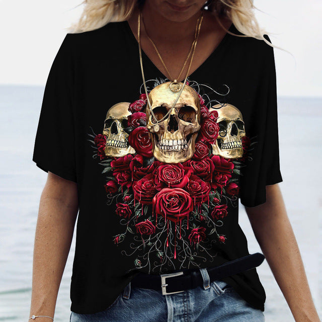 Person wearing a flattering fit, Maramalive™ Ladies' Printed V-Neck Tee | Chic Women's Graphic Tees featuring a design of three skulls surrounded by red roses, standing near a body of water.