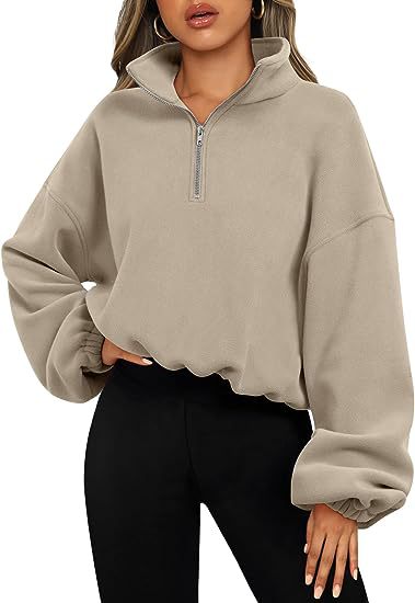 Person wearing a fashionable and simple beige Maramalive™ Loose Sport Pullover Hoodie Women Winter Solid Color Zipper Stand Collar Sweatshirt Thick Warm Clothing with a high collar and balloon sleeves, made from polyester fiber, paired with solid color black pants.