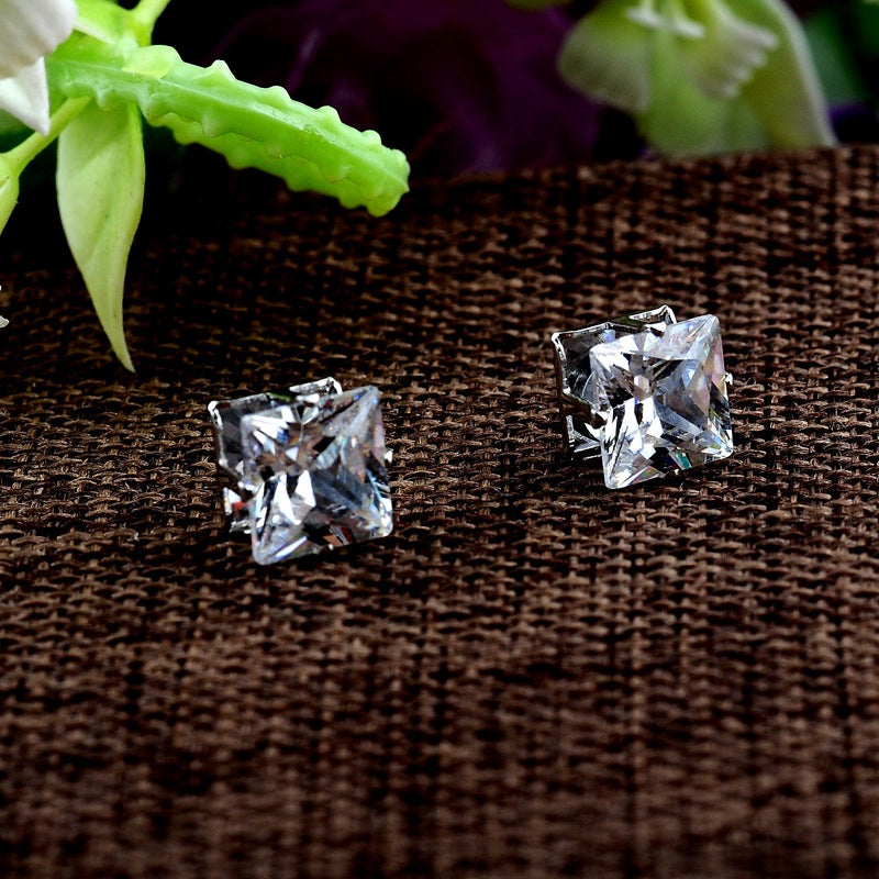 A pair of Popular Square Black And White Zircon Magnet Ear Studs by Maramalive™ on a brown cloth.