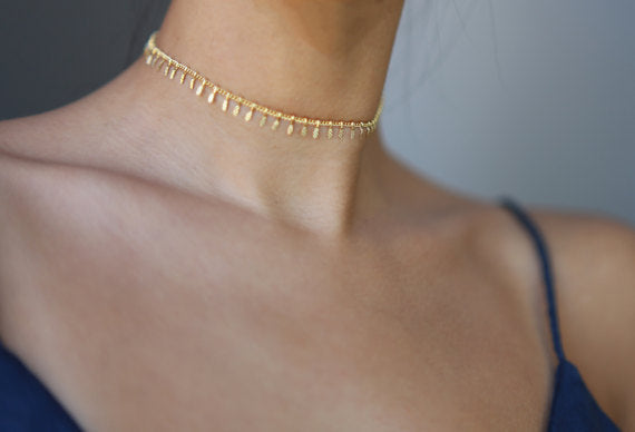 A woman wearing a Minimalist Copper Embossed Necklace with gold tassels from Maramalive™.