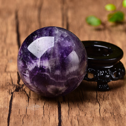 A Crystal Fantasy Purple Ball Polished Gemstone Crystal Ball from Maramalive™ sitting on top of a black stand.
