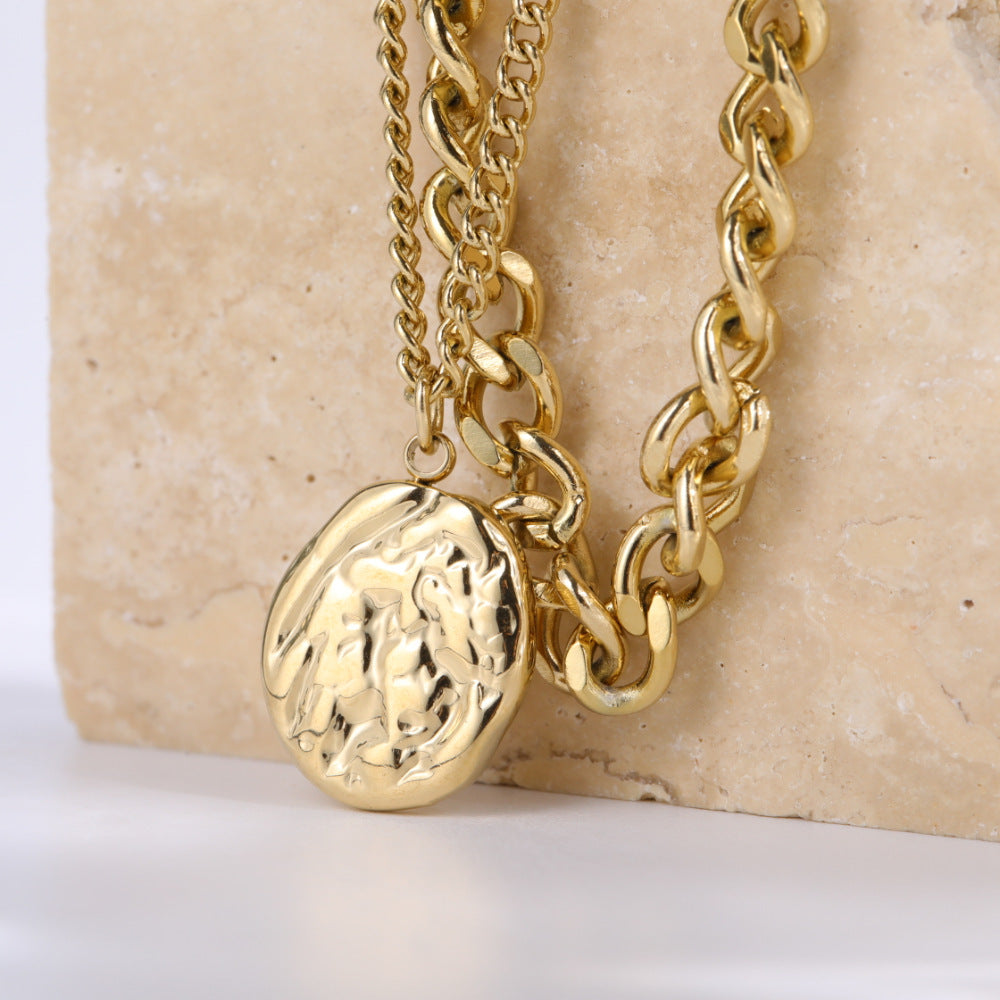 Two Retro Abstract Coin Pendant Necklace Double Layer necklaces on top of a stone.