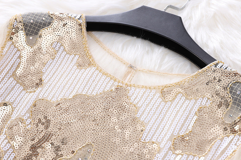 Close-up of a Petal Long Sleeve Beaded Sequins Slimming Lace Versatile Mesh Plus Size Top by Maramalive™ with gold and white patterns, featuring petal sleeves, hanging on a black hanger on a white fluffy surface.