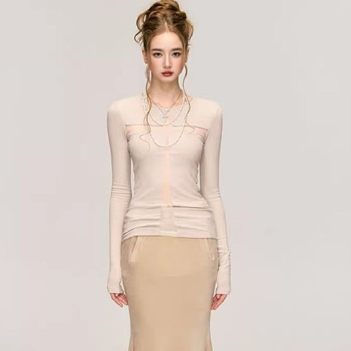 A woman with styled hair stands against a plain background, showcasing a Maramalive™ Fashion Long Sleeve Bottoming Shirt For Women and a light beige skirt, exuding pure desire style.