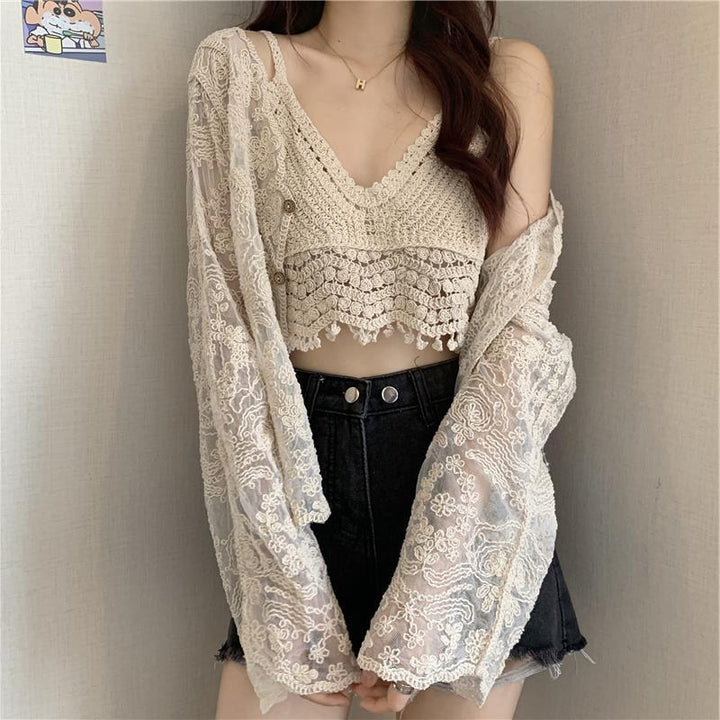 A person wearing a Maramalive™ Crocheted Two-piece Set Female Summer New Western Style Blouse Top, a lace cardigan, and high-waisted black shorts is standing against a plain background.