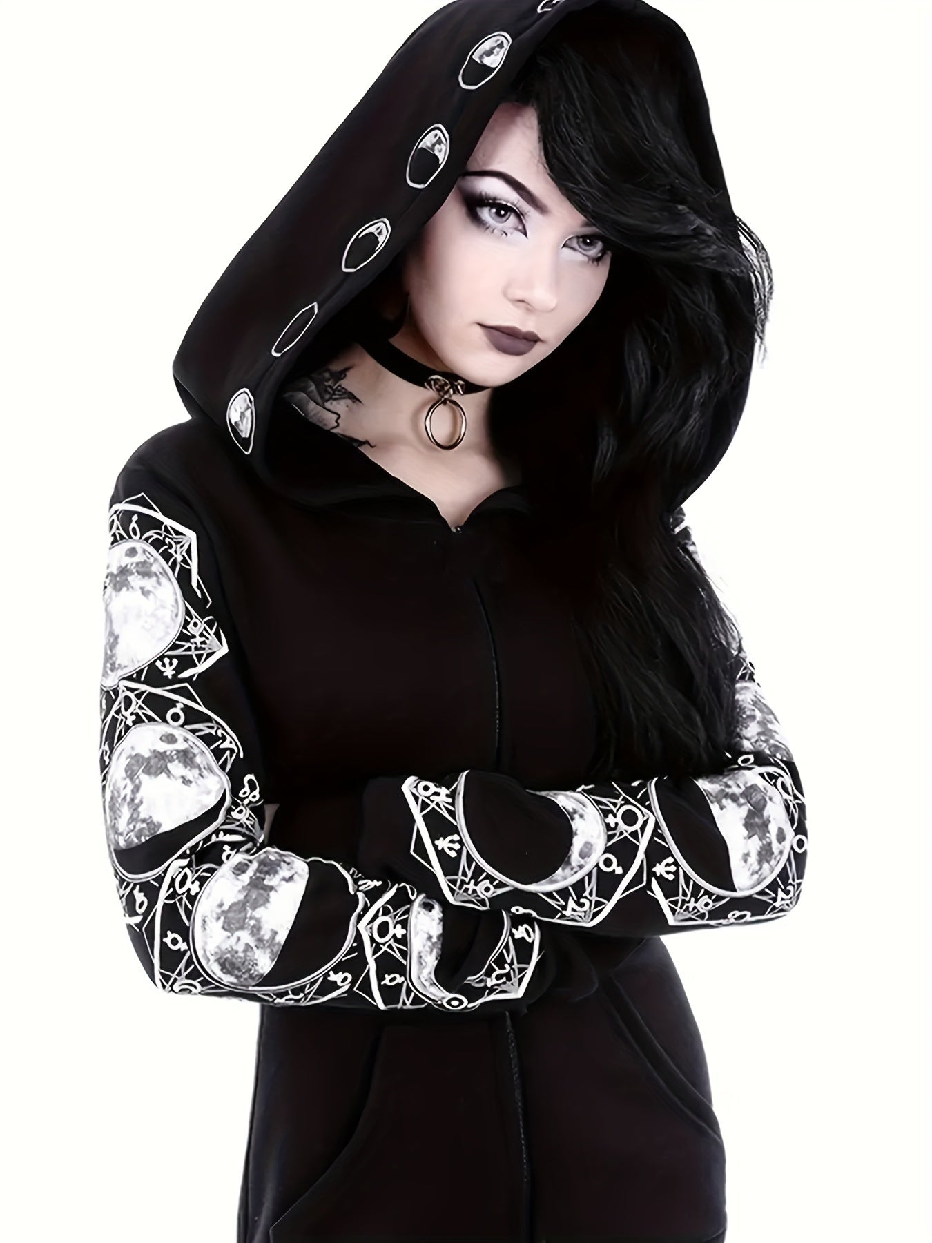 A woman with long black hair and bold makeup wears a casual black hoodie made of polyester, adorned with moon phase designs on the sleeves and hood, and a choker necklace with a ring. Her arms are crossed, wearing the Plus Size Gothic Sweatshirt, Women's Plus Moon Print Long Sleeve Zipper Slight Stretch Hoodie With Pockets by Maramalive™.