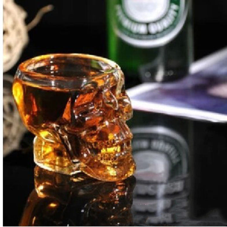 A Crystal Skull Wine Glass with a bottle of beer next to it.