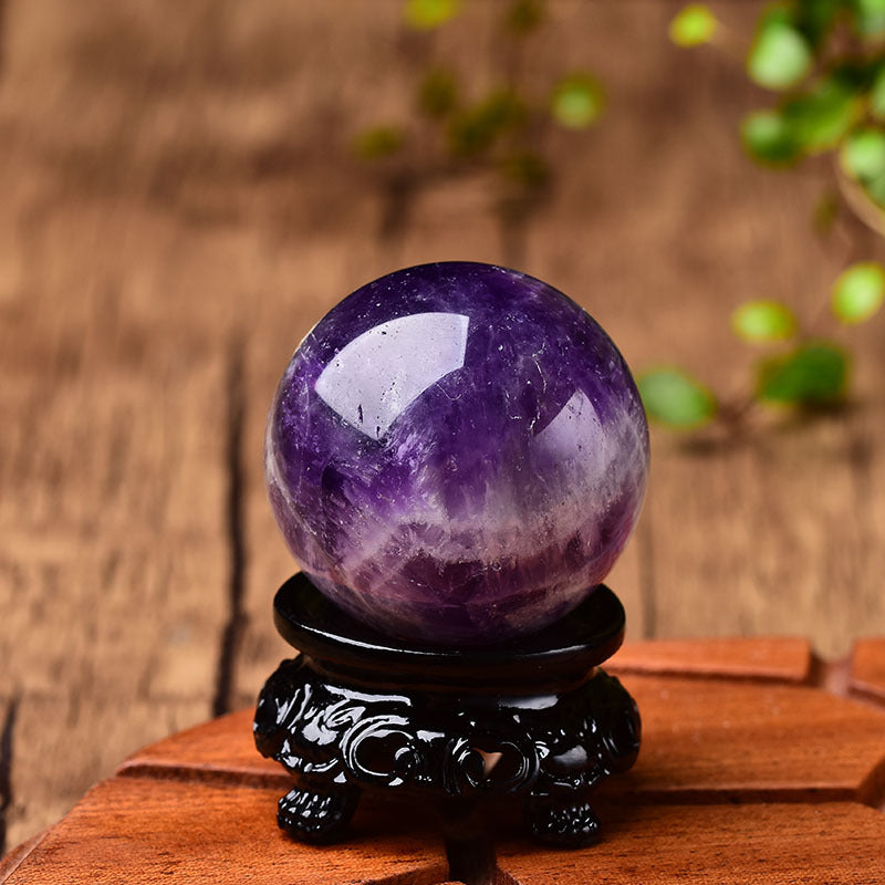 A Crystal Fantasy Purple Ball Polished Gemstone Crystal Ball from Maramalive™ sitting on top of a black stand.