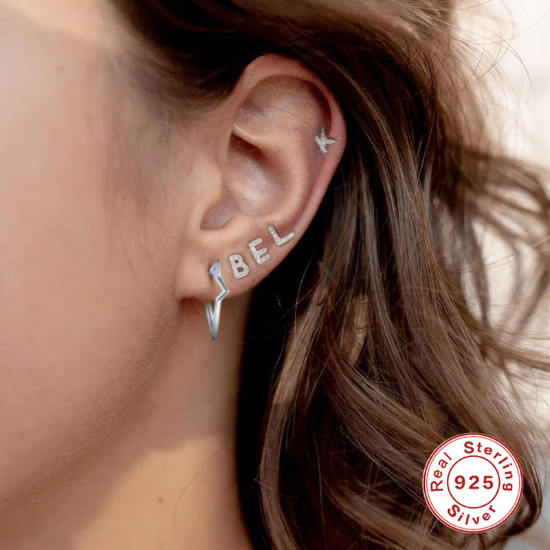 A woman wearing a pair of Maramalive™ Personalized Sterling Silver Letter Earrings with the word 'jebel' on them.