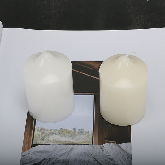 Two Maramalive™ candles decorated with cylindrical designs for dinner sitting on top of a book.