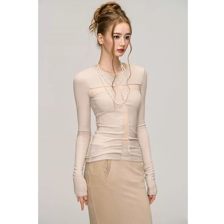 A woman is standing against a plain backdrop, exuding pure desire style. She is wearing the Maramalive™ Fashion Long Sleeve Bottoming Shirt For Women made of polyester fabric, paired with a beige skirt and adorned with a long necklace. Her hair is styled in a messy updo.