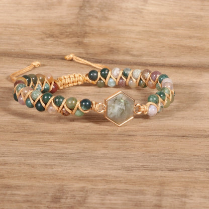A Gorgeous Agate Hexagonal Charm Braided Bracelet with green stone and gold beads on top of a rock by Maramalive™.