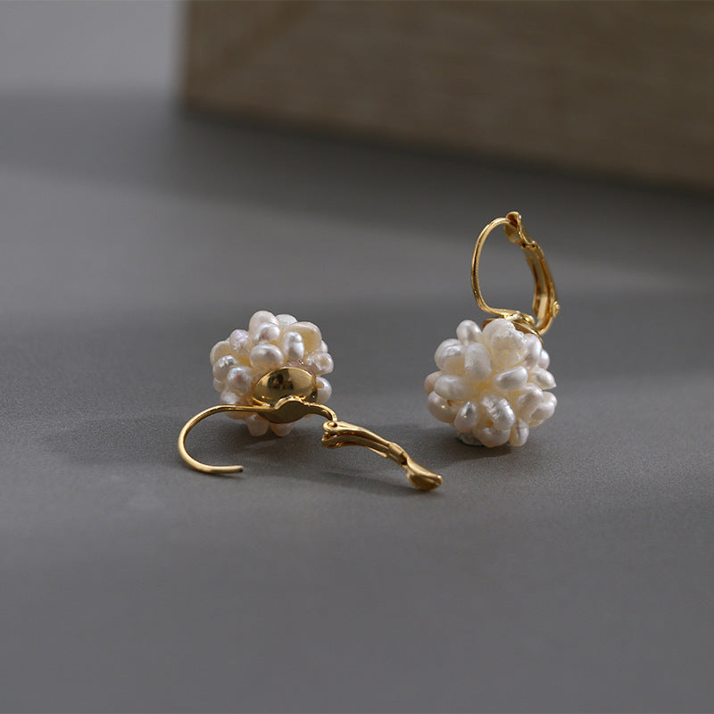 A pair of Minimalist Natural Pearl Earrings by Maramalive™ on a white cloth.