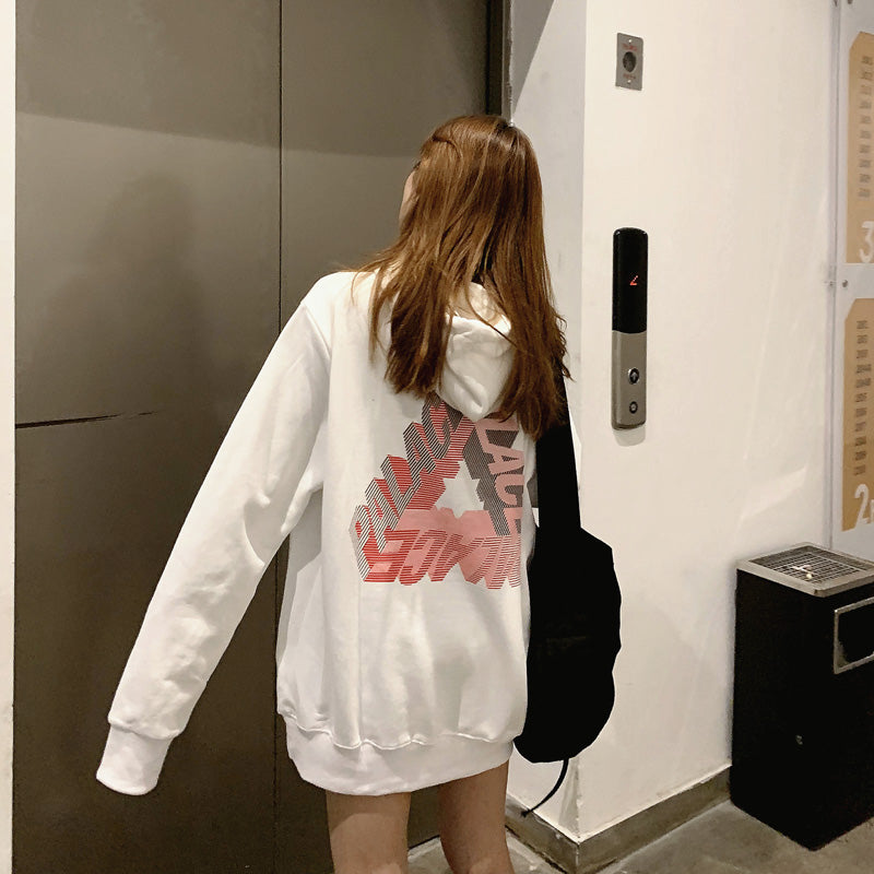 A person with long, light brown hair is wearing a white **Phantom hoodie by Maramalive™** and carrying a black bag, standing in front of an elevator door, embodying the essence of youth fashion perfect for autumn and winter.