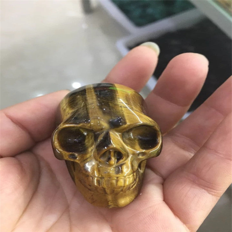 A hand holding a black Maramalive™ Natural crystal skull.