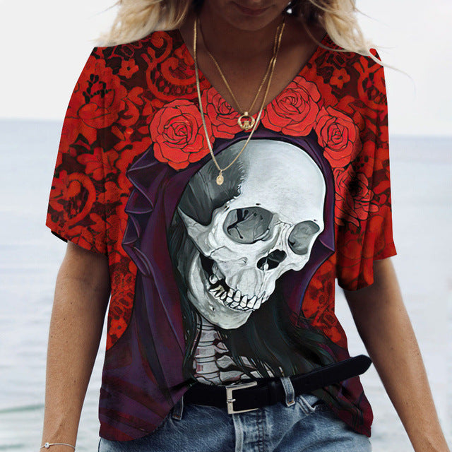 Person wearing a red Maramalive™ Ladies' Printed V-Neck Tee | Chic Women's Graphic Tees featuring a skull and roses design, standing by the water.