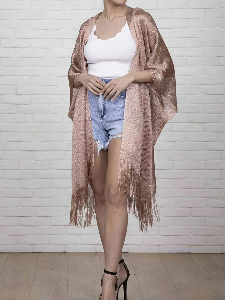 A person wearing a white top, denim shorts, high heels, and a Maramalive™ Plus Size Split Tassel Top, Casual Open Front Top For Summer, Women's Plus Size Clothing stands in front of a white brick wall.