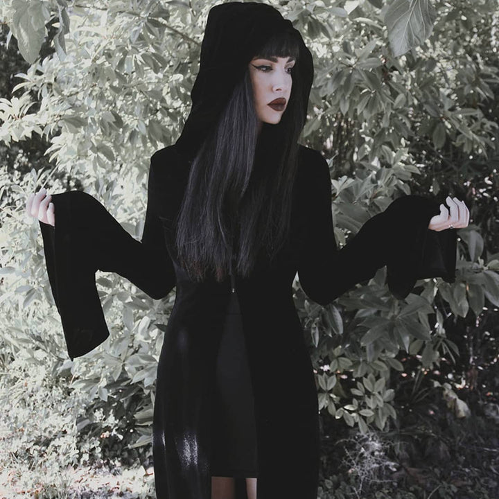 A girl in a Dark Punk Halloween Velvet Cloak - Gothic Underworld Black Cape, by Maramalive™, standing in the dark woods.