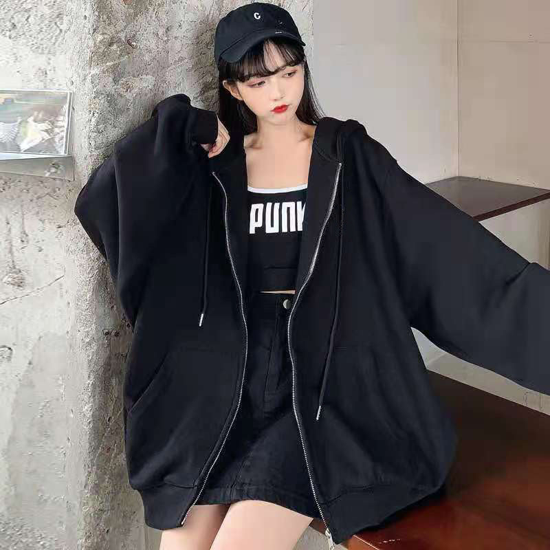 A young individual wearing a black hoodie, black crop top with "PUNK" text, black skirt, and black cap stands indoors near a textured wall and shelf. The Maramalive™ Comfy Zipper Hoodies for Fall: Hooded Sweatshirts & Sweaters add an edgy touch to their look.