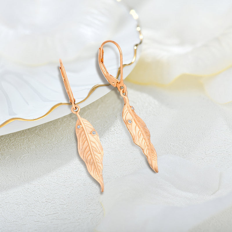 A woman wearing a pair of Maramalive™ FUNKY Vintage Versatile Rose Gold Leaf Sandblasted Zirconium Earrings.