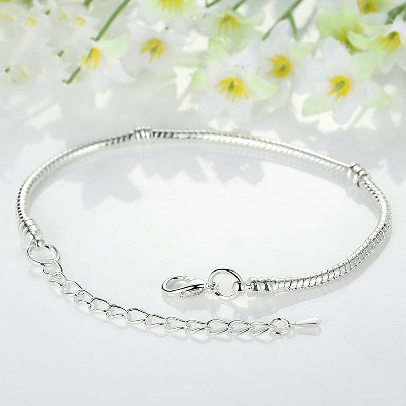 A Maramalive™ Fashion Ornament Creative Personality Snake Buckle Empty Charm Bracelet on a white table with flowers.