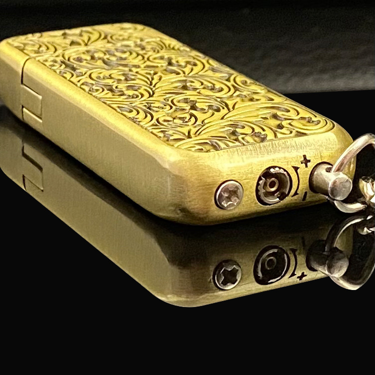 A gold and silver Buckle Butane Gas Inflatable Mini Antique Grinding Wheel Flame Lighter with a chain on it by Maramalive™.