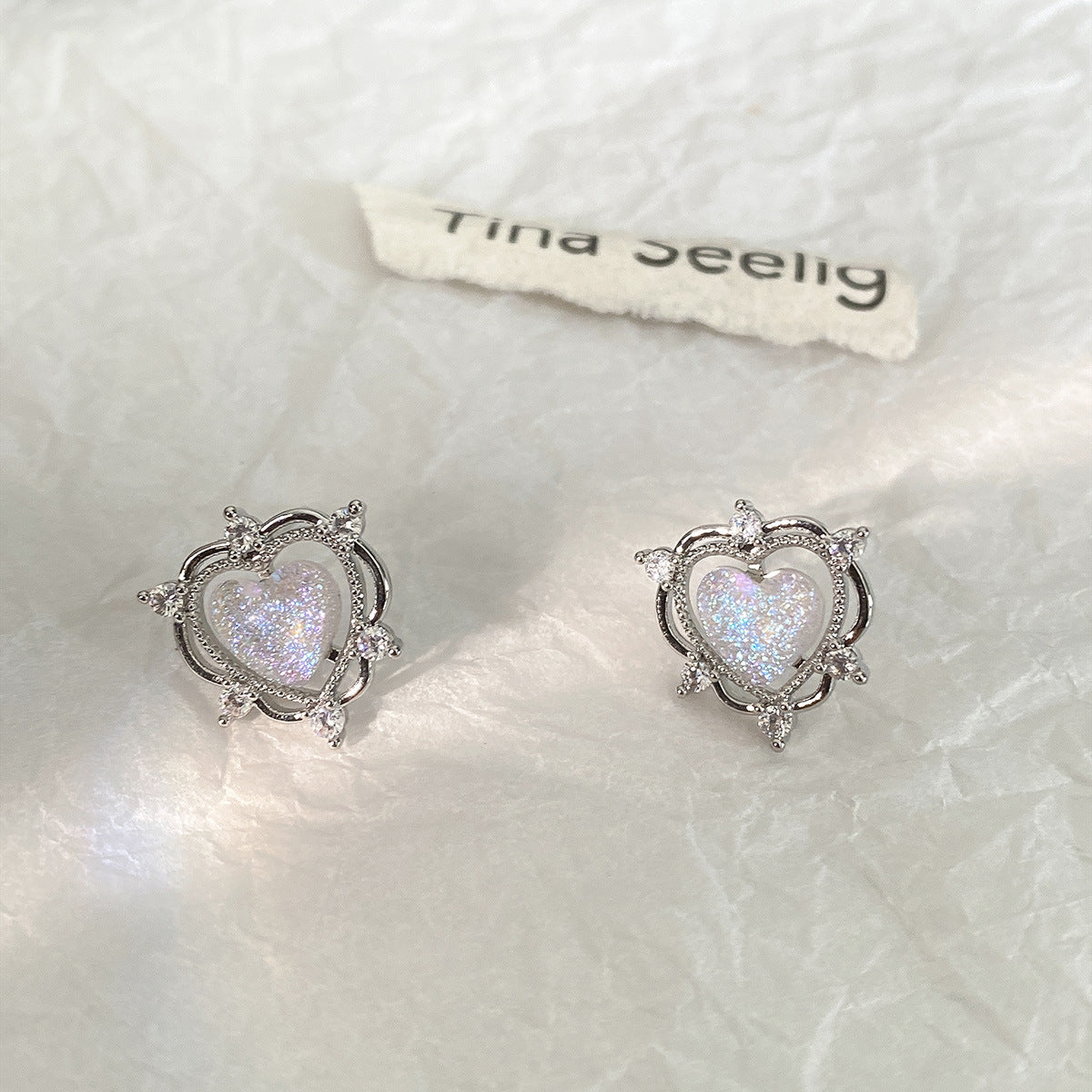 A pair of Sparkling Opal Heart Shape With Diamond Stud Earrings by Maramalive™ on a piece of paper.