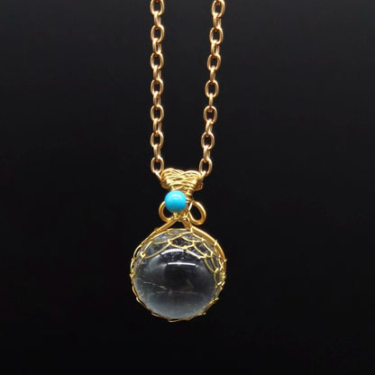A Crystal Ball Pendant - Natural White necklace with a black stone and turquoise beads by Maramalive™.