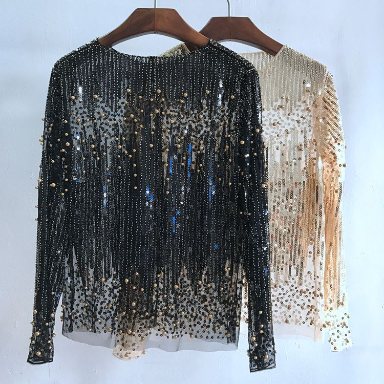 Two long-sleeve women's Fashion Bottoming Shirt Sequined Tops For Women on hangers, one in black and the other in gold, both adorned with shimmering tassels and intricate beadwork. Made from high-quality polyester fiber, these free-size sequined pieces by Maramalive™ add a touch of glamour to any outfit.