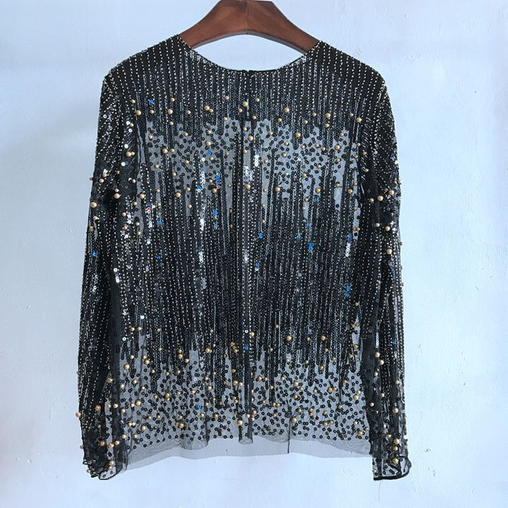 A sheer black Fashion Bottoming Shirt Sequined Top For Women with long sleeves, adorned with vertical stripes and scattered sequins, made from Polyester Fiber. Displayed on a wooden hanger against a plain wall, it is available in Free size for ultimate comfort and style. This stylish piece is part of the Maramalive™ collection.