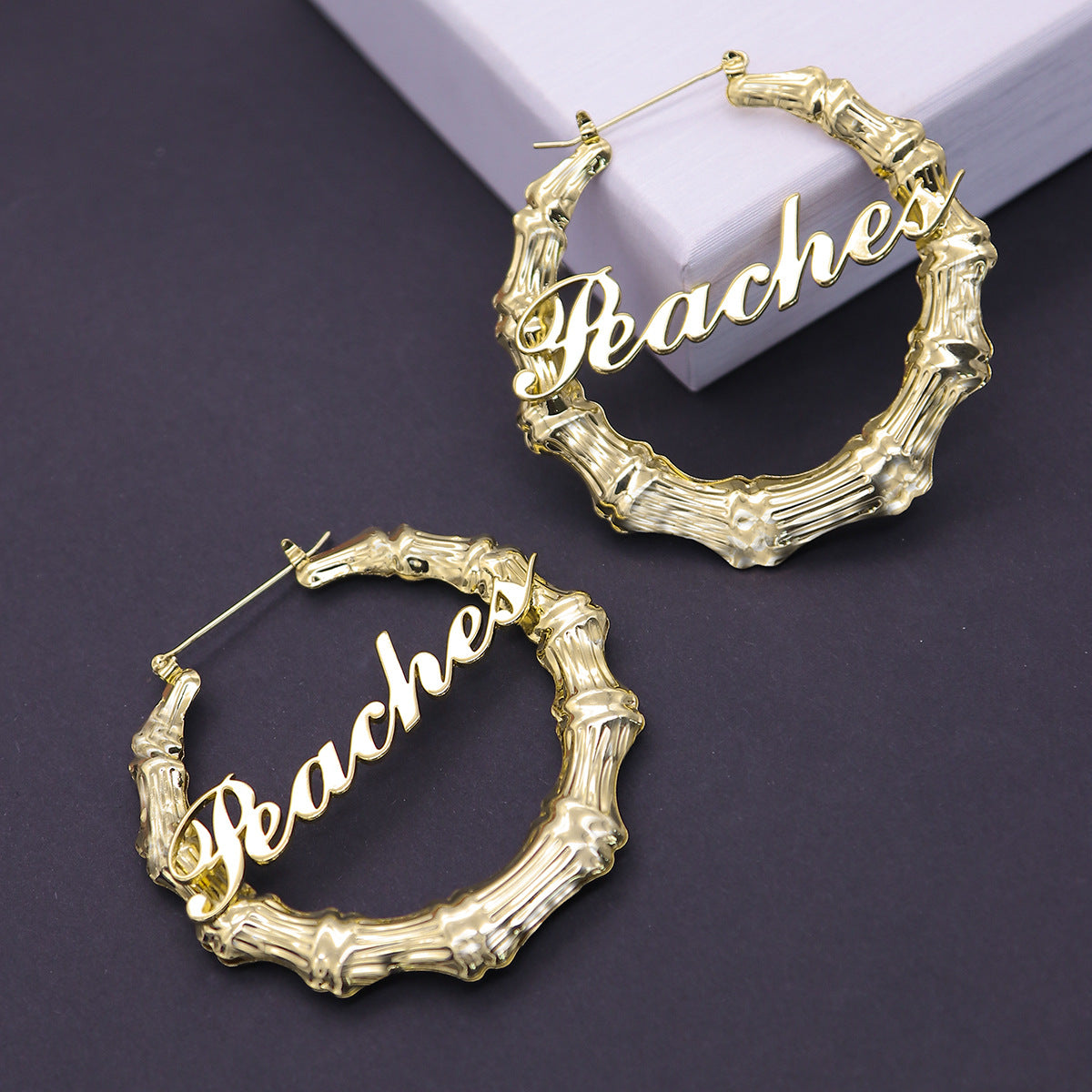 A pair of Customized Titanium Steel Name Bamboo Earrings Round with the word beach by Maramalive™.