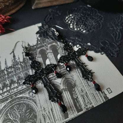 A pair of Gothic Anhe earrings by Maramalive™ on a table next to a bottle of wine.