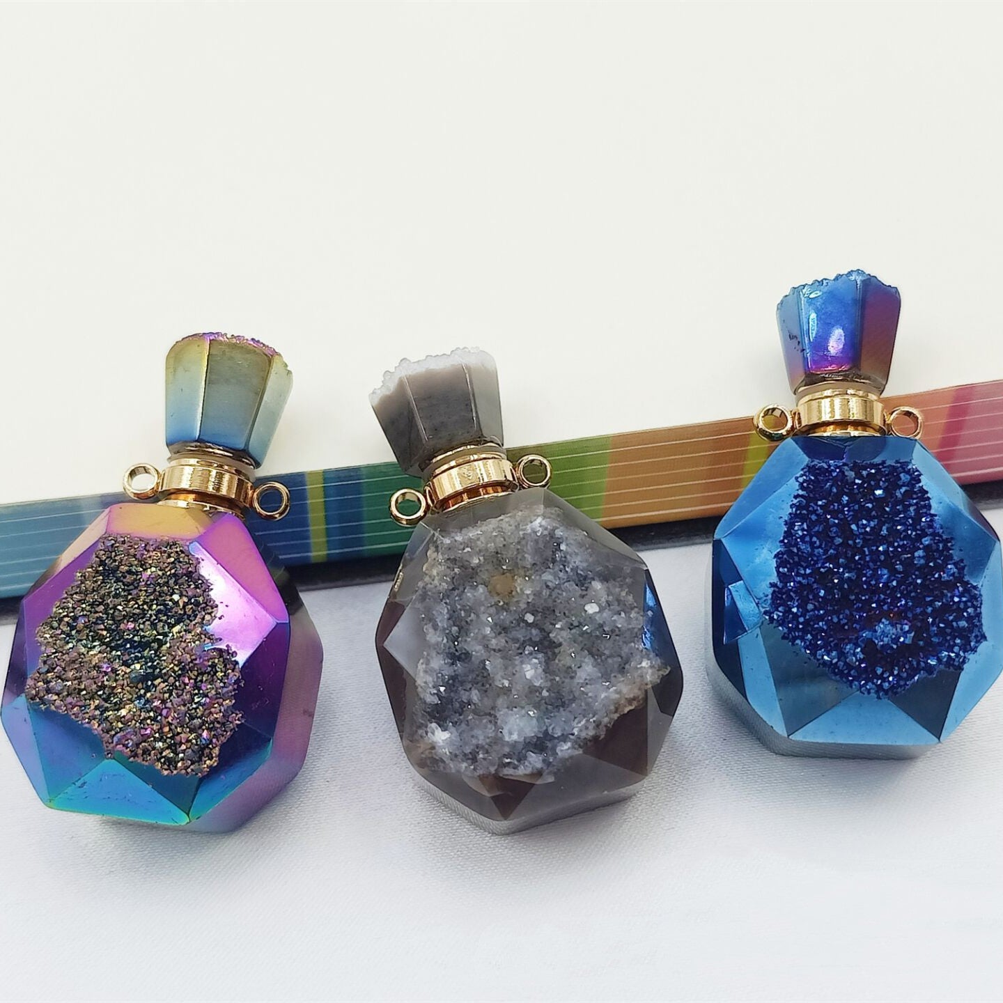 A set of three Agate Crystal Pendant perfume bottles on a table, by Maramalive™.