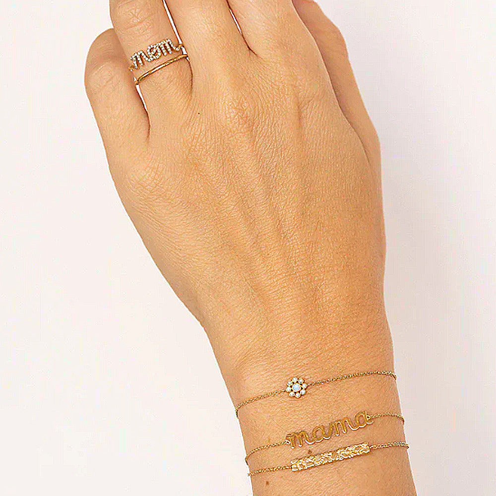 A woman's hand with a Silver Letter Bracelet by Maramalive™ and a ring on it.
