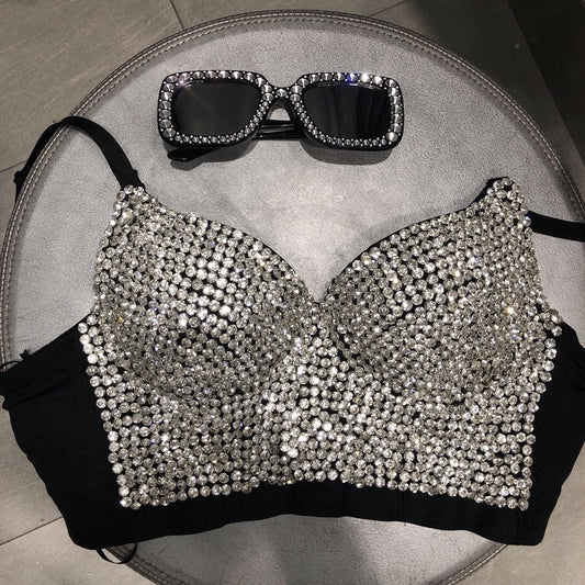 A black Gypsophila shining studded waistcoat strapless tube top strap adorned with numerous shiny rhinestones, paired with matching square-shaped sunglasses, rests stylishly on a round grey surface. This chic Maramalive™ design elevates any casual look.