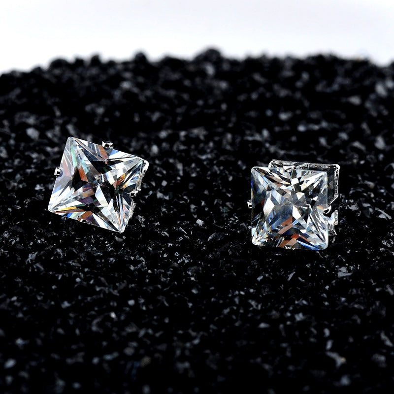 A pair of Popular Square Black And White Zircon Magnet Ear Studs by Maramalive™ on a brown cloth.