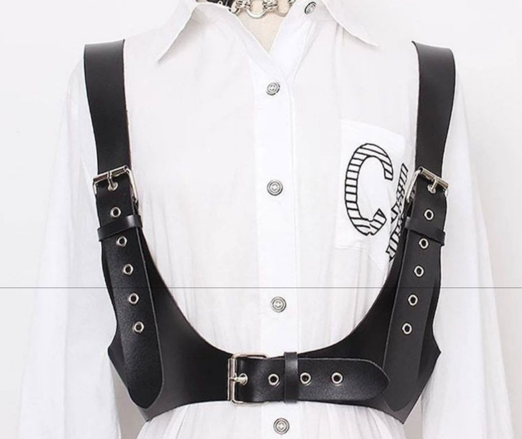A woman wearing a Gothic Bold Strap Vest - Punk Vegan-Friendly Leather Body Belt by Maramalive™ and a white shirt.