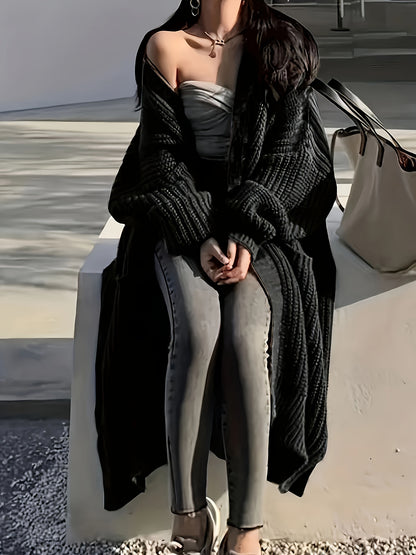 A person sits on a ledge wearing a black oversized coat, light gray top, skinny jeans, and sandals. They have long, dark hair flowing over their Maramalive™ Plus Size Open Front Loose Knit Cardigan, Casual Long Sleeve Long Length Cardigan With Pocket and a large beige bag is placed next to them.
