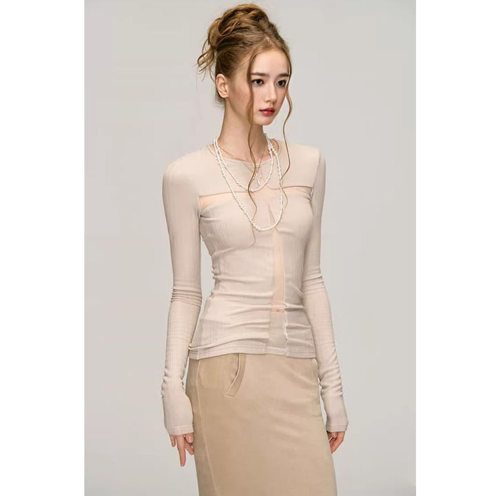 A woman with styled hair is standing against a plain background, showcasing a light, long-sleeved women's top made from polyester fabric and a beige skirt. Her pure desire style is accentuated by the Maramalive™ Fashion Long Sleeve Bottoming Shirt For Women and a long beaded necklace.