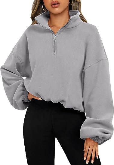 A person wearing a light gray, long-sleeve, high neck zip-up Maramalive™ Loose Sport Pullover Hoodie Women Winter Solid Color Zipper Stand Collar Sweatshirt Thick Warm Clothing paired with black pants.