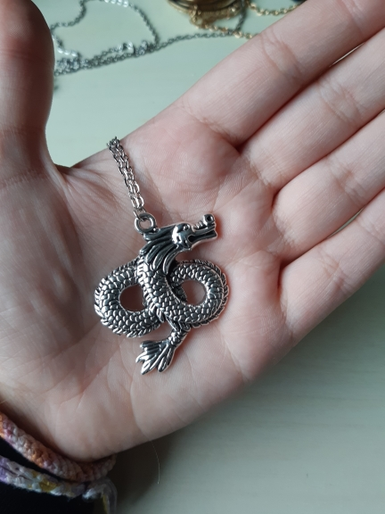 A Maramalive™ silver dragon necklace on a black background.