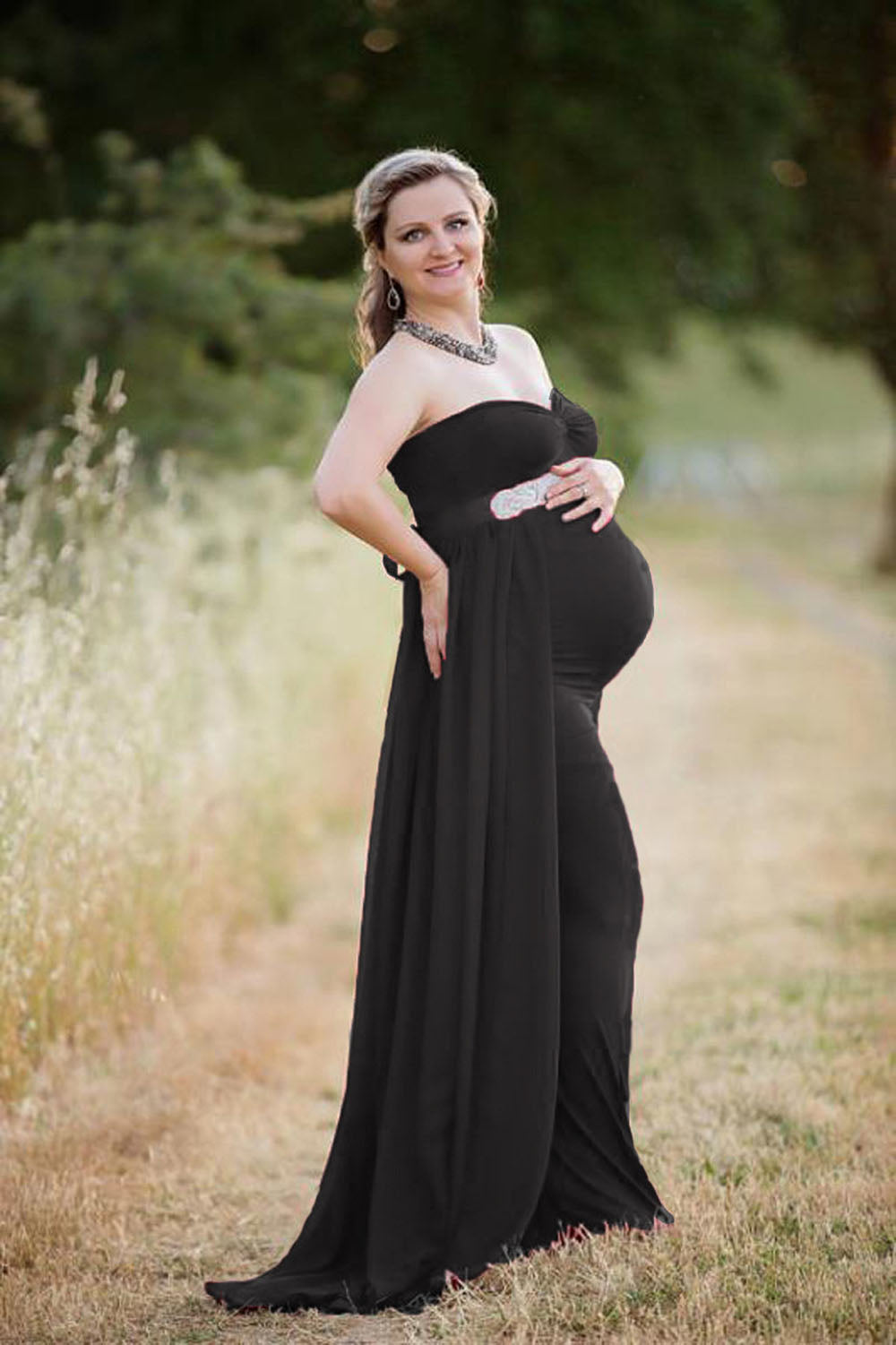 A pregnant woman in a red Maramalive™ chiffon mop skirt dress posing in a garden.