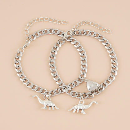 A woman's hands are holding two Maramalive™ Creative Dinosaur Stainless Steel Chain Couple Love Heart-shaped Bracelets.