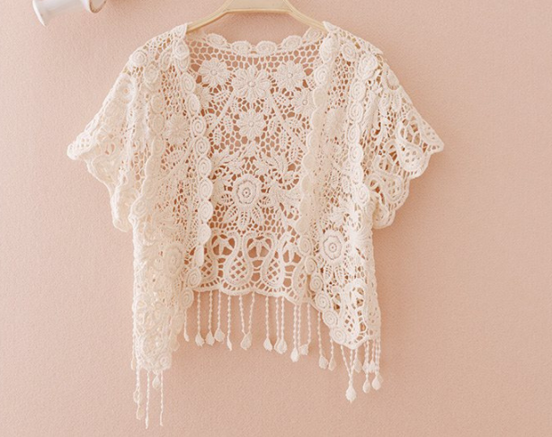 A loose type Maramalive™ white lace cardigan hanging on a pink wall.
