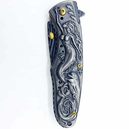 Two Maramalive™ Outdoor Survival Knife Camping Mermaid Folding with different designs on top of a skateboard.